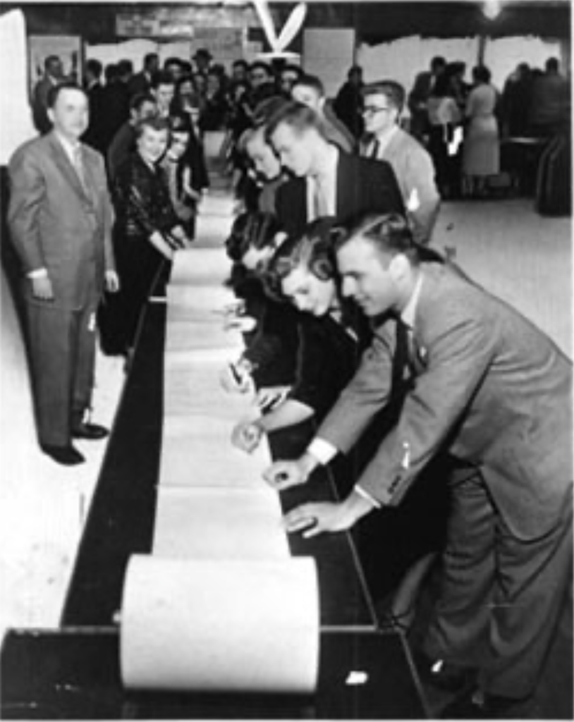 a black and white photo showing large crowd of CUD students signing an extremely long petition to demand a permanent four-year campus